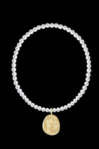 A delicate beaded bracelet with a small gold coin pendant featuring a palm tree design, displayed on a clean white background.