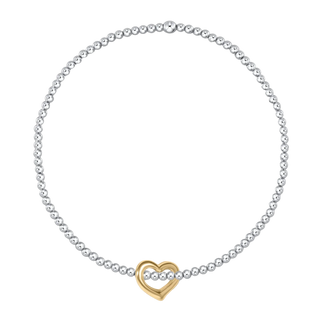 A delicate silver beaded necklace with a central gold heart-shaped charm, displayed on a clean white background.