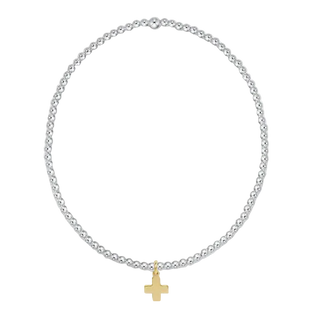 A silver beaded necklace with a small gold cross pendant, displayed on a clean white background.