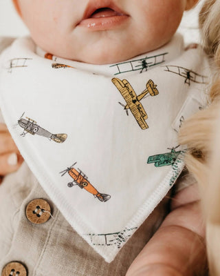 Baby wearing a bib with airplane pattern, close-up shot.