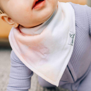 Baby wearing a colorful bib with a brand logo on a blurred background