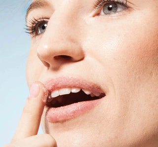 Close-up of a person with their finger on their lips against a light blue background