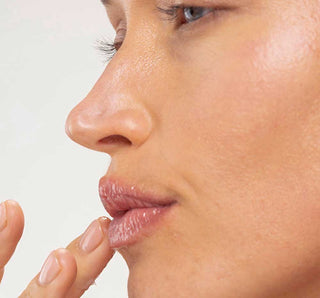 Close-up of a woman's face with a focus on her lips and hand.