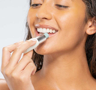 Woman applying lip balm to her lips with a white background