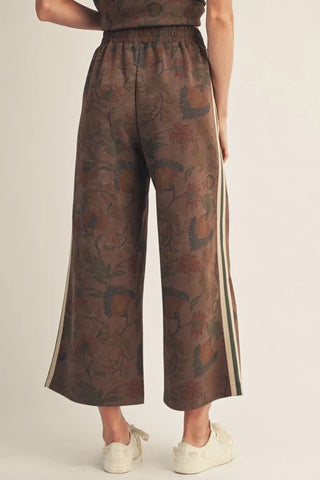 Patterned pants with side stripes worn by a person on a beige background