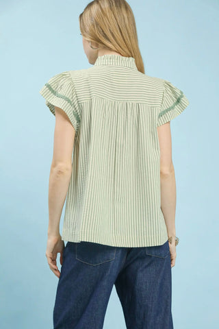 Woman wearing a light green striped shirt with ruffled sleeves against a light blue background