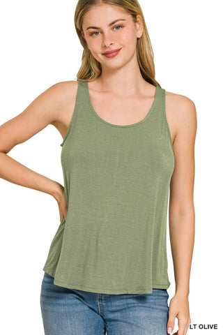 Woman wearing a light olive green tank top and blue jeans on a white background