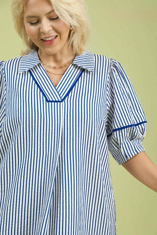 Woman wearing a blue and white striped shirt against a light green background