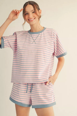 Woman wearing a pink and blue striped pajama set on a beige background