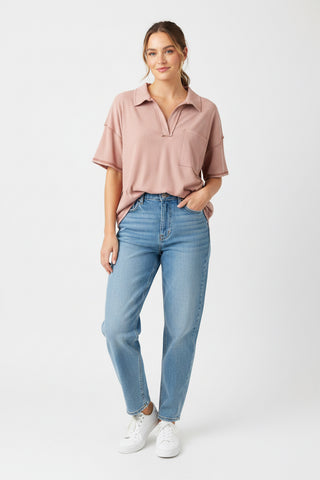 Woman wearing a pink polo shirt and blue jeans on a white background