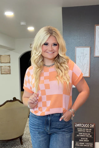 Woman standing in a store with checkered shirt and jeans, surrounded by furniture and decor.