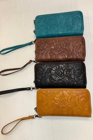 Four floral embossed wallets in blue, brown, black, and tan on a light background