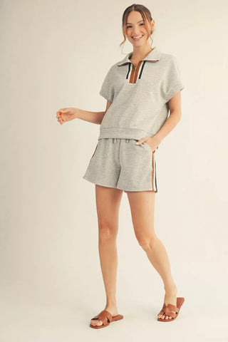 Woman wearing a gray outfit with shorts on a plain background