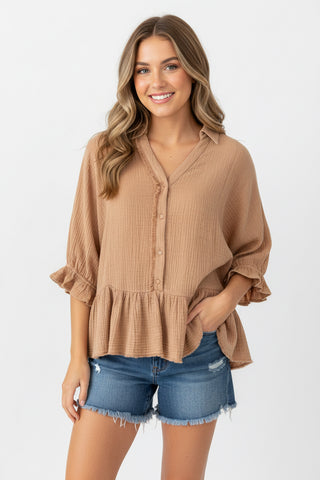 Woman wearing a brown blouse and denim shorts on a white background