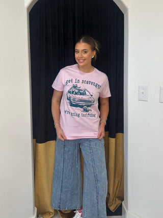 Person wearing a pink t-shirt with text and graphics, standing in a doorway.