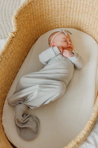 Newborn baby wrapped in a lying in a woven basket on a soft surface.