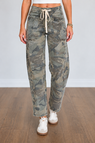 Front view of Risen camouflage jeans featuring a high-rise waist, cream drawstring, front patch pockets, paneled seams, and a relaxed barrel-leg fit with ankle-length hems.