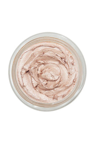 A top-down view of a clear round jar filled with a swirled, creamy cosmetic product in a light champagne pink shade, set against a solid white background.