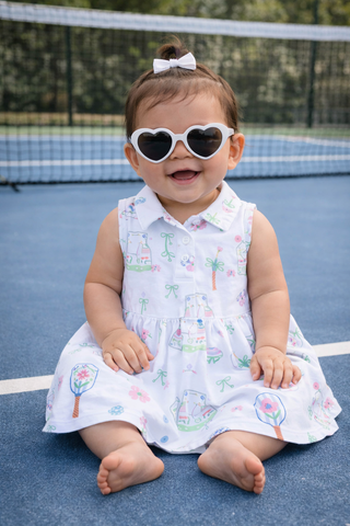 Child wearing heart-shaped sunglasses on a tennis court