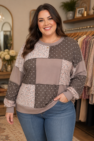 A woman modeling a patchwork sweatshirt with brown, beige, and white polka dot panels, paired with blue jeans in a boutique setting.