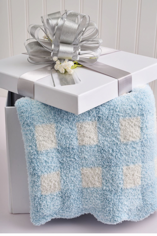 Blue and white checkered blanket draped over a white table with a silver bow on a light gray background