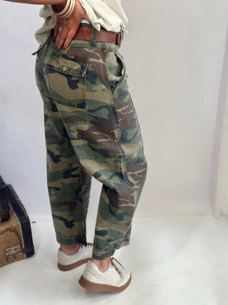 Camouflage pants worn by a person on a white background