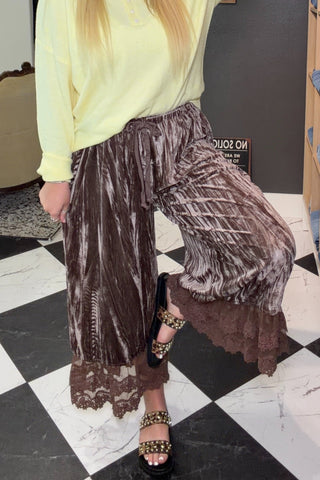 Woman in a yellow top and brown pants standing in a store with shelves and furniture.