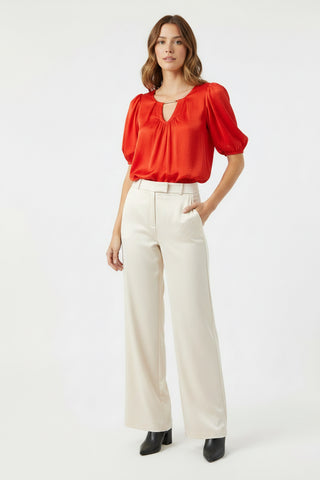 Woman wearing a red blouse and white pants on a white background
