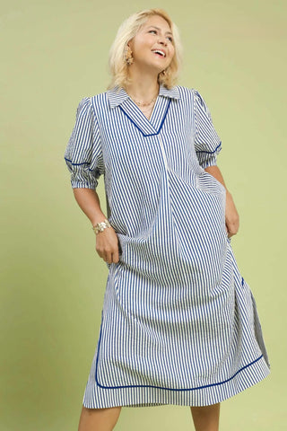 Woman wearing a blue and white striped dress against a light green background