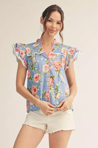 Woman wearing a floral blouse and white shorts on a beige background