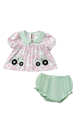 Baby outfit with floral top and green bloomers on a fluffy white surface