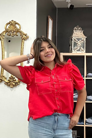 Woman wearing a red shirt and blue jeans standing in a room with decorative elements.