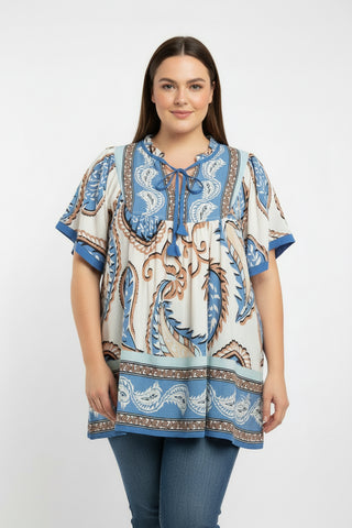 Woman wearing a patterned blue and beige blouse on a white background