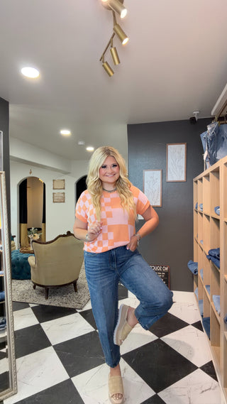 Woman posing in a room with checkered floor and furniture