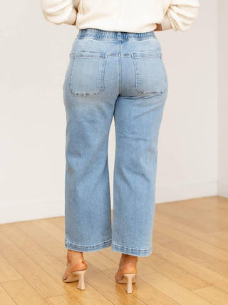 Light blue jeans worn by a person on a wooden floor with a white background