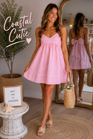 Woman in a pink and white striped dress standing in a room with decorative elements.