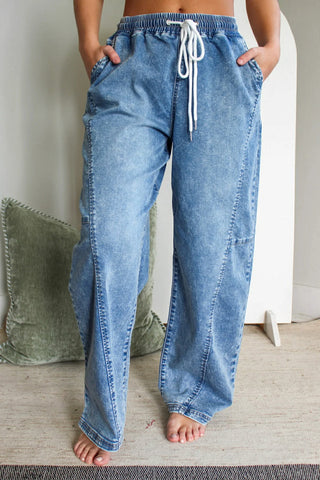 Blue denim pants with a drawstring waist being worn by a person on a neutral background.