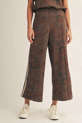 Person wearing brown floral-patterned pants on a plain background