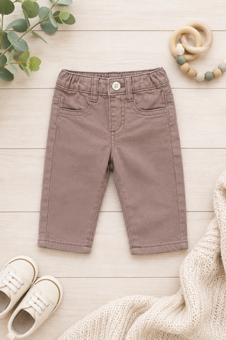 Brown children's pants on a light wooden floor with shoes and a toy in the background