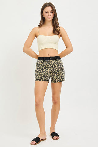 Woman wearing a white crop top and leopard print shorts on a white background