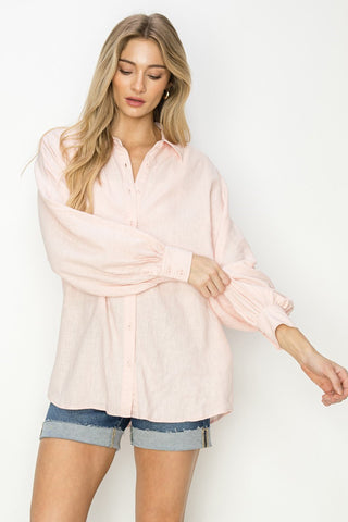 Woman wearing a light pink blouse and denim shorts on a white background