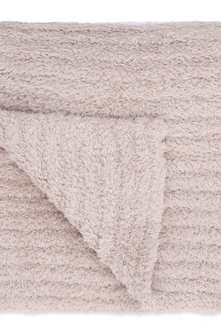 A close-up of a soft, textured bath towel in a light taupe-beige color, folded over to show its plush terry fabric.