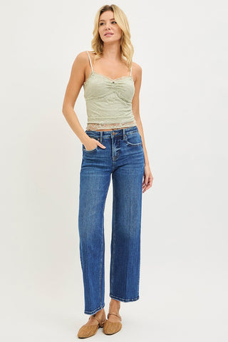 Woman wearing a green top and blue jeans on a white background