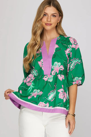 Woman wearing a green floral blouse with purple accents on a white background