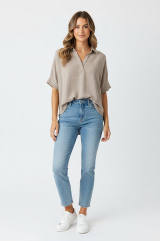 Woman wearing a beige blouse and light blue jeans on a white background