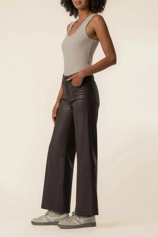 A model is shown from the side wearing dark brown wide-leg pants, a light gray ribbed tank top, and gray sneakers against a plain beige studio background.