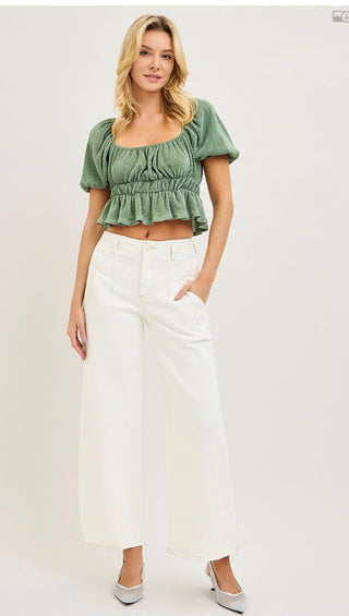 Front view woman in white jeans green top white background 