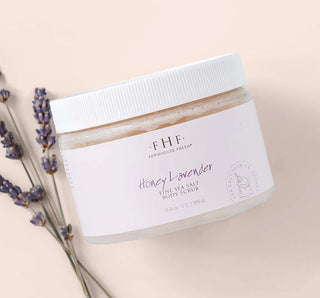 Jar of Farmhouse Fresh Honey Lavender body scrub with lavender sprigs on a beige background