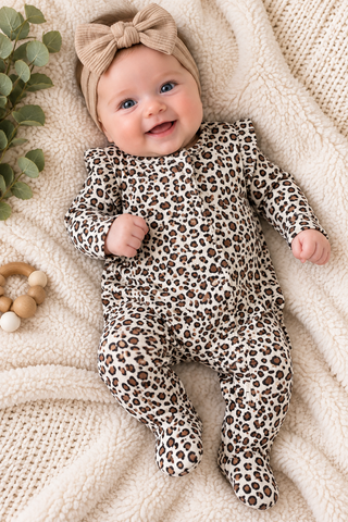 Baby laying on blanket wearing leopard footie.
