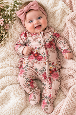 
BABY WEARING FOOTIE LAYING ON BLANKET.